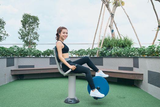 Asian woman exercising at outdoors gym playground equipment