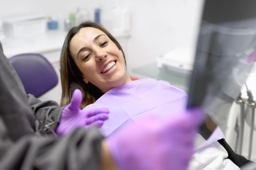 Female dentist pointing at patient's X-ray image in dental office. High quality photo