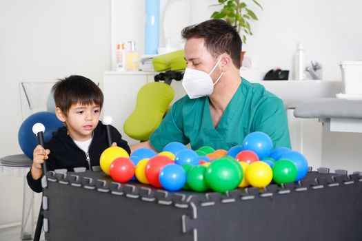 Child with cerebral palsy on physiotherapy in a children therapy center. Boy with disability doing exercises with physiotherapists in rehabitation centre. High quality photo.