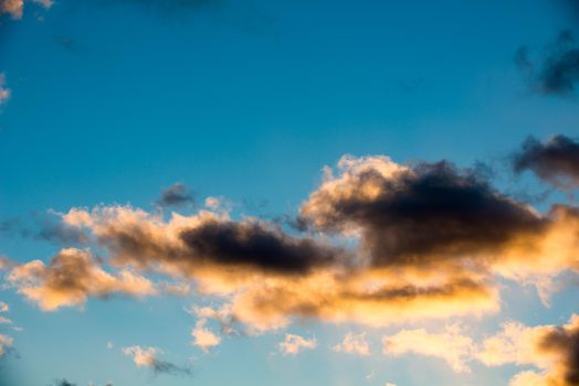 Puffy and colorful sunset clouds closeup over blue sky