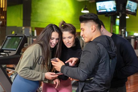 Group of young people using and looking at mobile phone together. High quality photo