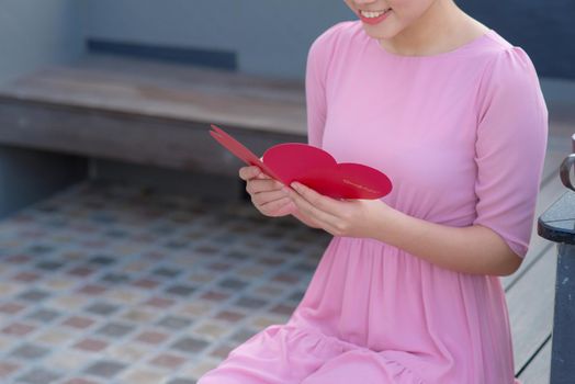 Image of happy beautiful female reading romantic postcard with big red heart, attractive woman got sensual greeting card, valentine day,love concept