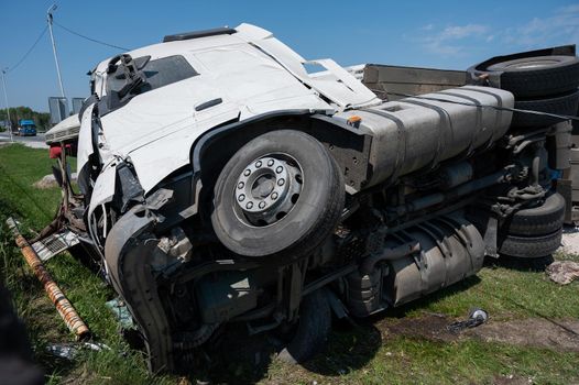 The truck is lying on its side in a car accident on the highway.