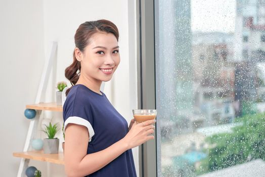 Attractive mixed female lifestyle enjoying a cup of tea looking out the window