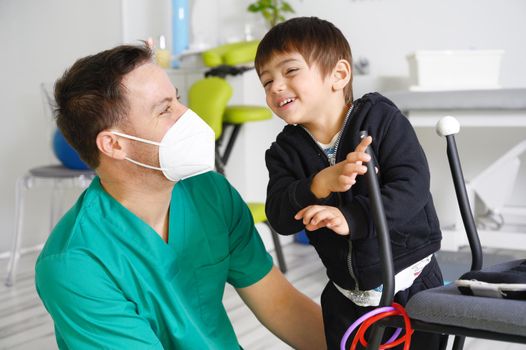 Child with cerebral palsy on physiotherapy in a children therapy center. Boy with disability doing exercises with physiotherapists in rehabitation centre. High quality photo.