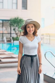 Portrait of pretty cheerful woman on summer season at resort swimming pool