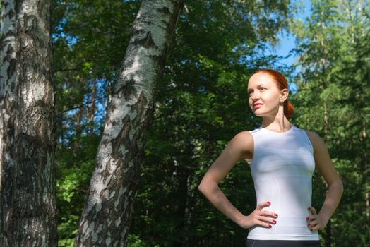 Young woman showing standing with hands on her waist in forest