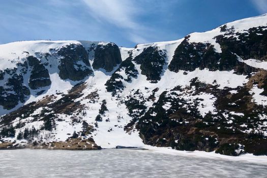 High on the mountainside lies snow on a sunny summer day