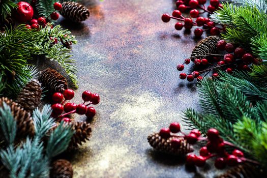 Christmas card concept with frame made with green fir branches, red decoration balls and berries on concrete background