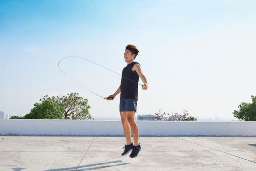 fitness, sport, people, exercising and lifestyle concept - man skipping with jump rope outdoors