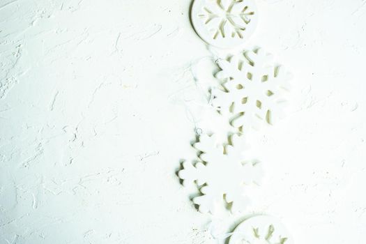 Christmas frame made with ceramic snowflakes on white concrete background with copy space