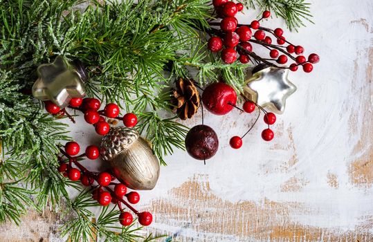 Christmas card concept with frame made with green fir branches, red decoration balls and berries on concrete background