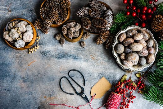 Christmas card concept with frame made with green fir branches, red decoration balls and berries on concrete background