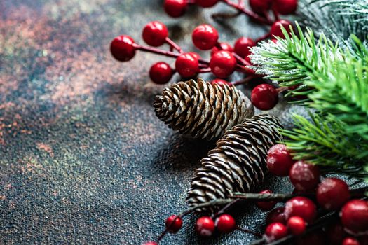 Christmas card concept with frame made with green fir branches, red decoration balls and berries on concrete background
