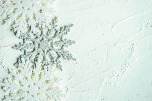 Christmas frame made with ceramic snowflakes on white concrete background with copy space
