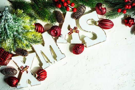 Christmas card concept with frame made with green fir branches, red decoration balls and berries on concrete background