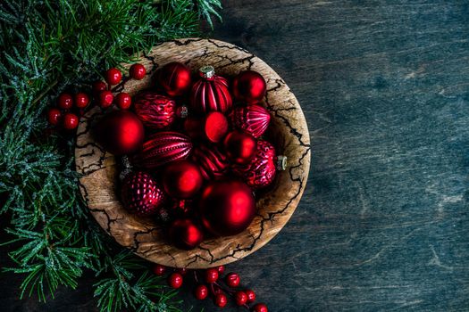 Christmas card concept with frame made with green fir branches, red decoration balls and berries on concrete background