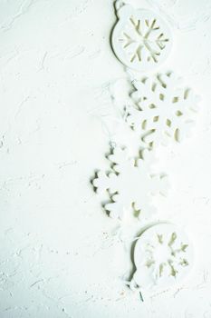 Christmas frame made with ceramic snowflakes on white concrete background with copy space