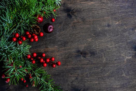 Christmas card concept with frame made with green fir branches, red decoration balls and berries on concrete background