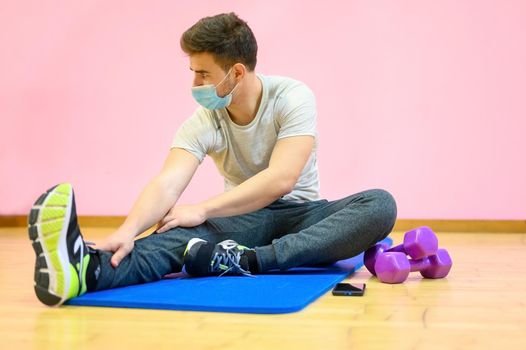 Fitness man streching Relaxing after training, wearing protective face mask during Covid 19 new normal. High quality photo