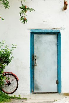 Red bicycle parked near the entrance of a small house