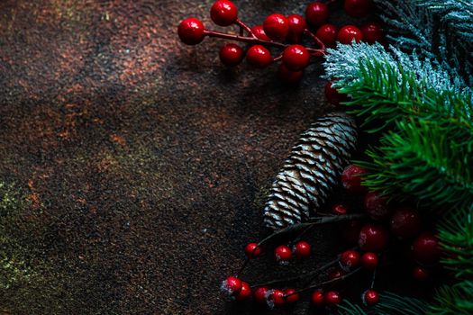 Christmas card concept with frame made with green fir branches, red decoration balls and berries on concrete background