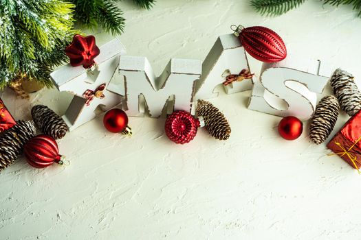 Christmas card concept with frame made with green fir branches, red decoration balls and berries on concrete background