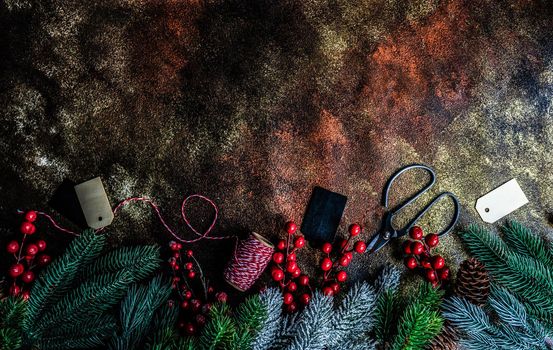 Christmas card concept with frame made with green fir branches, red decoration balls and berries on concrete background