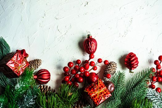 Christmas card concept with frame made with green fir branches, red decoration balls and berries on concrete background