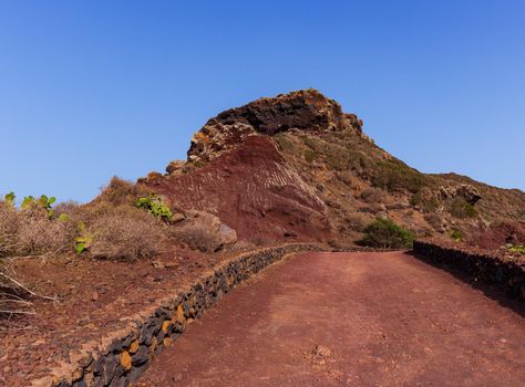 Path to the Volcano Monte Nero of Linosa. Characteristic country road with the dry stone wall built with lava stones