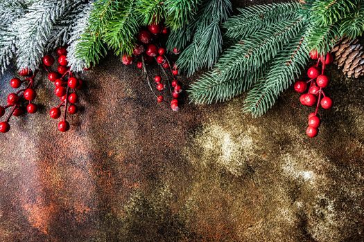 Christmas card concept with frame made with green fir branches, red decoration balls and berries on concrete background