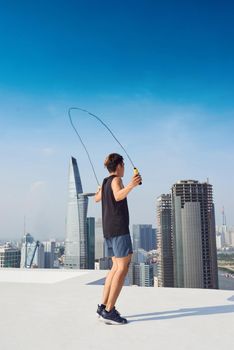 fitness, sport, people, exercising and lifestyle concept - man skipping with jump rope outdoors