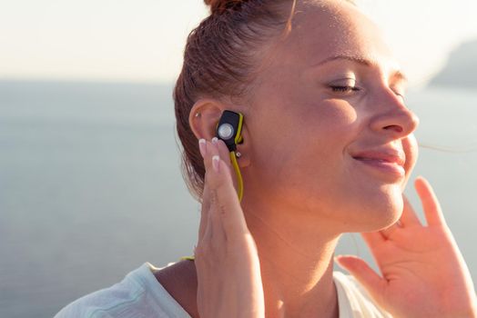 Fitness girl with sport in-ear wireless headphones - Caucasian female athlete woman wearing Bluetooth earphones