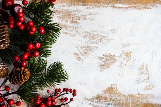 Christmas card concept with frame made with green fir branches, red decoration balls and berries on concrete background