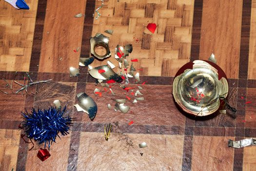 Shards from a broken Christmas tree toy lie on the floor. Broken decoration
