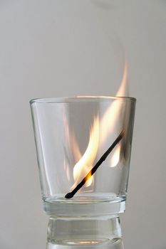 Remains of a dying match in a transparent glass on a light background. Concept, symbol