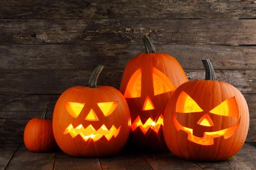 Glowing Halloween pumpkins on old wooden background