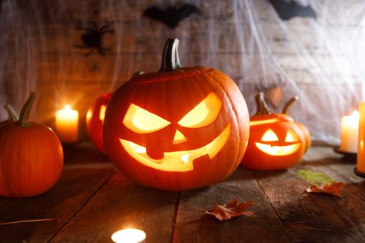 Halloween, decorations and holidays concept - pumpkins with bats, spider web and candles