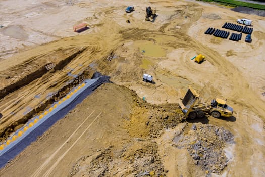 Aerial panoramic view dump truck unloading process on construction site at work preparing ground for new housing