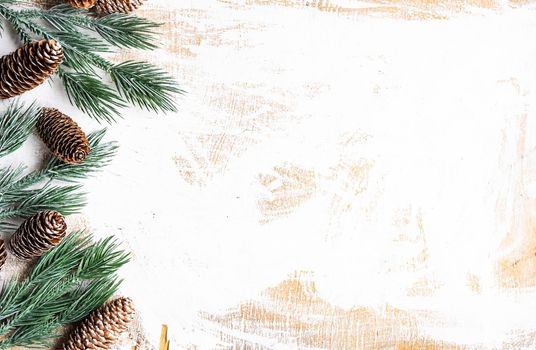 Fir tree with cones on vintage white wooden table as a Christmas frame concept