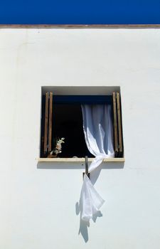 Window with white curtains on white facade in Almeria, Spain