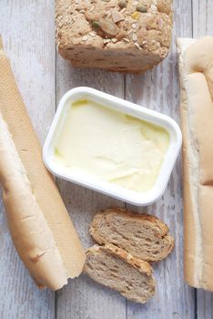 slice of butter and whole meal bread on chopping board .