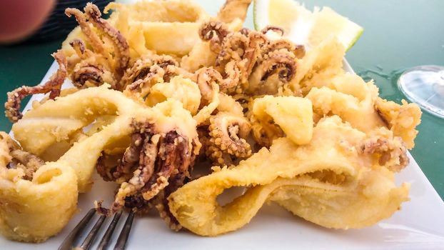 Typical Spanish tapa of battered fried squids with lemon in a restaurant