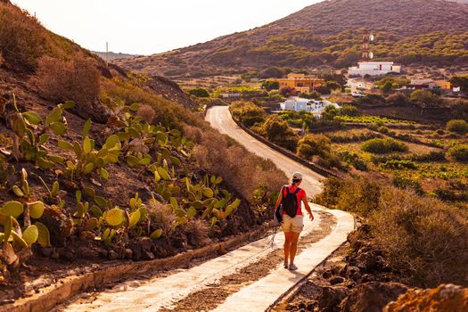 Woman walking on the path of the volcano called Monte Nero, Linosa. Sicily. Italy