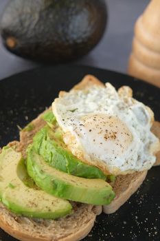 Avocado, brown bread, egg and rosemary on table.