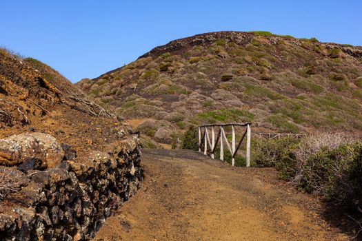 Path to the Volcano Monte Nero of Linosa. Characteristic country road with the dry stone wall built with lava stones