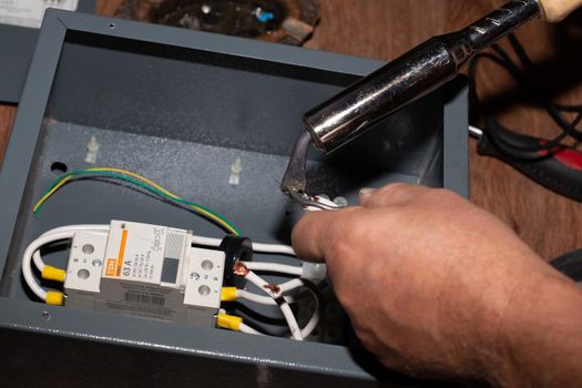 Soldering the elements of the electrical circuit of the modular contactor of the heating system of the cottage. Anapa, Russia-04.09.2021.