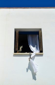 Window with white curtains on white facade in Almeria, Spain