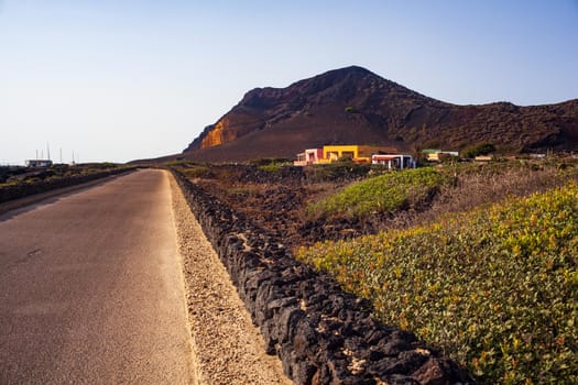 Road with dry stone wall . The Monte Nero Volcano on the background. Linosa, Sicily