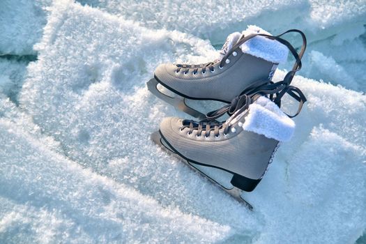 A pair of female figure skates lie on the ice